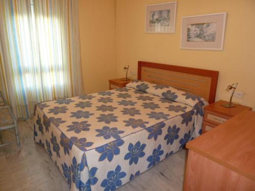 贝纳尔马德纳滨海赌场酒店的一间卧室配有一张带蓝白色毯子的床