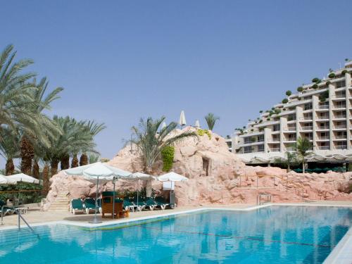 埃拉特丹埃拉特酒店的一座游泳池,其背景是一座度假村