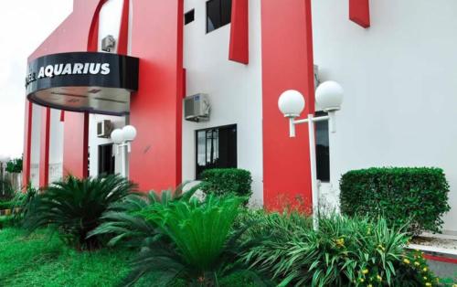 AriquemesAquarius Hotel Aquarius的一座红白色的建筑,前面有植物