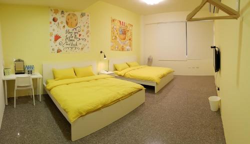 横冈下美好关西民宿的配有两张床铺的客房配有黄色床单和书桌