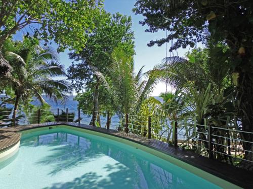 维拉港天堂湾度假酒店的一座种有树木的游泳池,一座背景为大海的游泳池