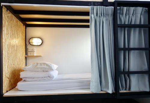 台南老曼船长青年旅馆的双层床,配有窗户和一些枕头