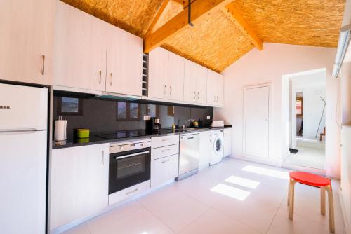 加亚新城Aguda Beach Charming House By PortoProperties4You的厨房配有白色橱柜和红色凳子