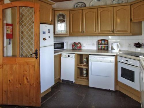 巴林罗布Delia's Cottage的厨房配有白色家电和木制橱柜