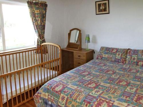 巴林罗布Delia's Cottage的一间卧室配有一张床、一张婴儿床和一面镜子