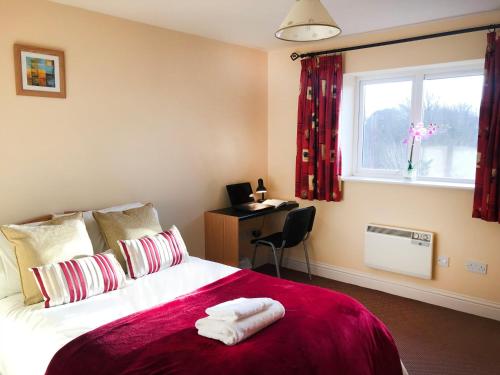 特拉利Kings Court Holiday Apartments的一间卧室配有一张带书桌的床和窗户。