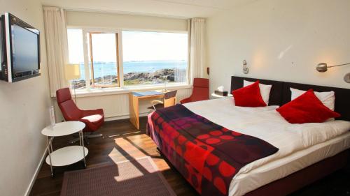 伊卢利萨特北极酒店的一间卧室配有一张带红色枕头的床和一扇窗户