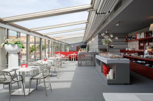 巴勒莫博塔菲里斯酒店及水疗中心的餐厅设有白色的桌椅和窗户。