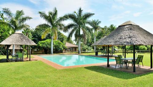 科玛蒂普特大象漫步休养度假酒店的一个带桌椅和遮阳伞的游泳池