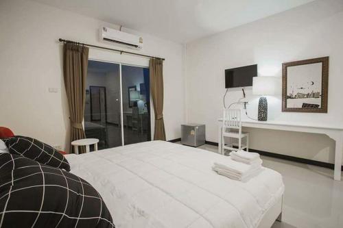 乌隆他尼班扬酒店的白色卧室配有一张大床和一张书桌