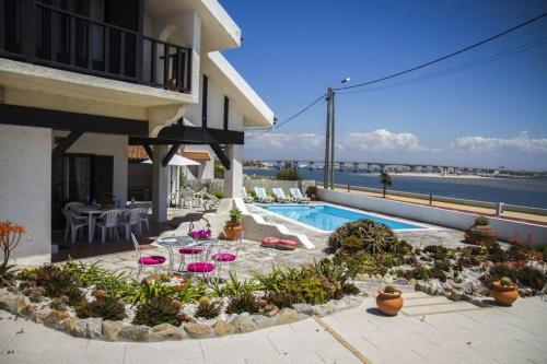 诺瓦海岸Casa do Bico da Biaritz的庭院设有游泳池、桌子和椅子。