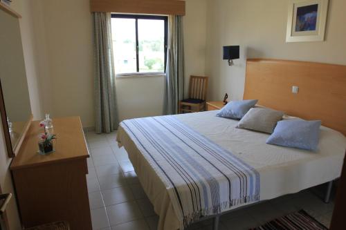 阿尔沃尔Apartamento T1 Quinta Nova - Alvor的一间卧室配有一张带蓝色枕头的床和一扇窗户。