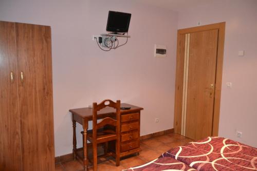 索里亚阿勒瓦科斯旅馆的一间卧室配有一张桌子和一张床,墙上配有电视。