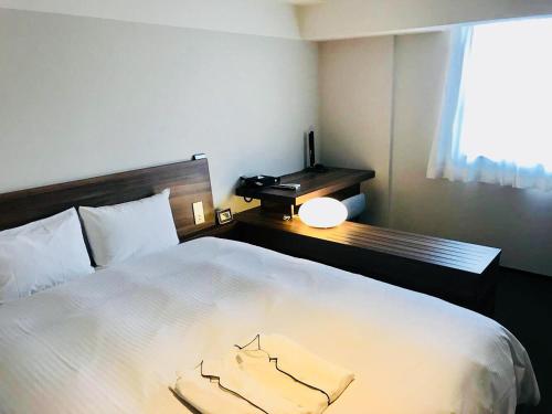 神户布伦扎酒店 的一间卧室配有一张带书桌的床和窗户。