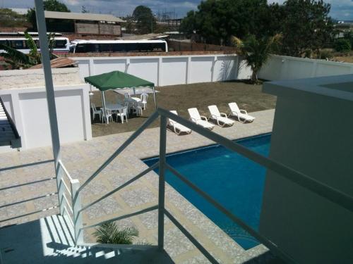 曼塔Manta Airport Hotel的一个带躺椅和绿色遮阳伞的游泳池