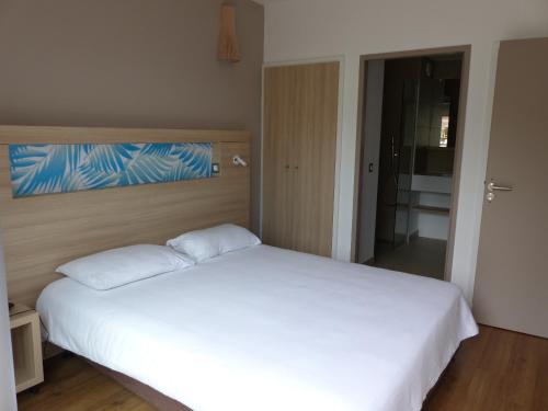 科内Le Pacifik Kone的卧室配有白色的床和大型白色床单