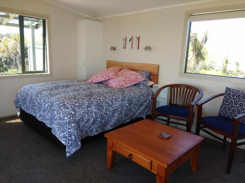 Cape FoulwindOkari Cottage的一间卧室配有一张床、两把椅子和一张桌子