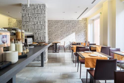 米兰Hotel Tiziano - Gruppo Mini Hotel的一间带桌椅的餐厅以及砖墙