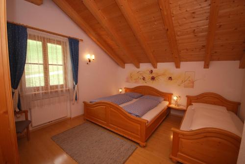 圣坎迪朵Im Kranzhof的一间卧室设有两张床、一个窗口和木制天花板。