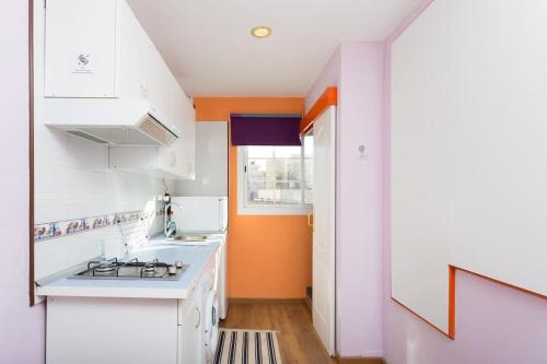 圣伊西德罗Estudio moderno y acogedor, a 5 minutos de la playa的厨房配有白色橱柜和橙色墙壁