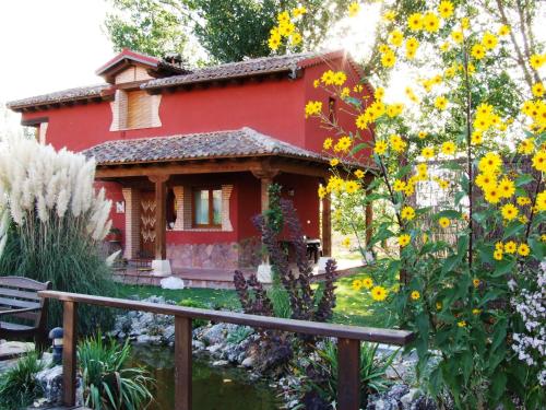 TuréganoA Toca Casas Rurales en Turegano Segovia的院子里的红色房子,花黄色