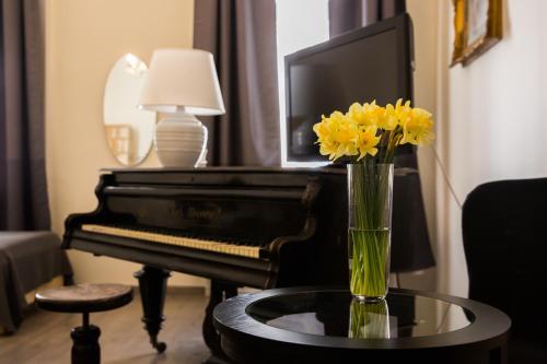 布达佩斯Ozone Private Rooms的钢琴旁边的桌子上一束黄色花瓶