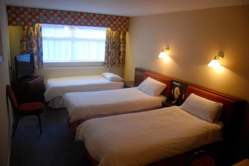 罗瑟勒姆Brecon Hotel Sheffield Rotherham的酒店客房设有三张床和窗户。