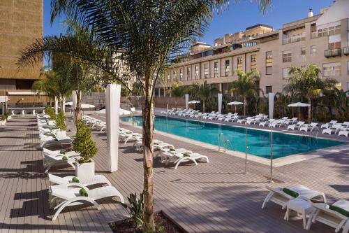 塞维利亚布雷罗斯美利亚酒店的一个带躺椅的度假游泳池和一间酒店