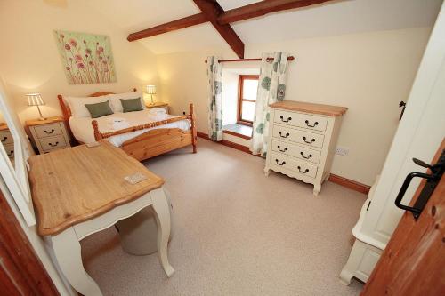斯旺西Cilhendre Holiday Cottages - The Dairy的一间卧室配有一张床和一张桌子