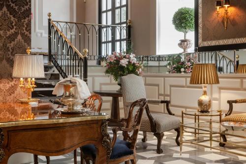 马德里Relais & Châteaux Heritage Hotel的一间带桌椅和楼梯的客厅