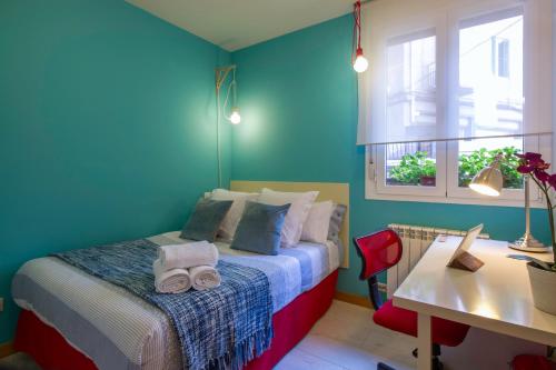 圣塞瓦斯蒂安Ondarreta Beach Apartment con parking free y Aire acondicionado的一间卧室配有一张蓝色墙壁的床和一张书桌