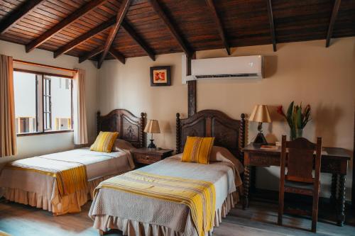 利马安提瓜米拉弗洛雷斯酒店的一间卧室设有两张床、一张桌子和一个窗口。