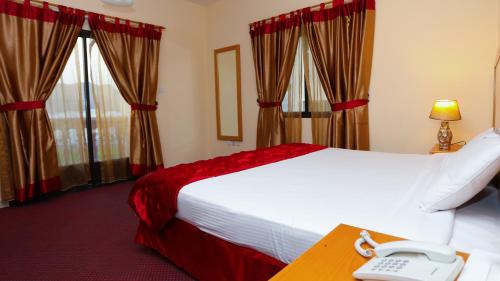 马斯喀特Al Shorouq Hotel Apartments的酒店客房,配有一张床和一张书桌上的电话