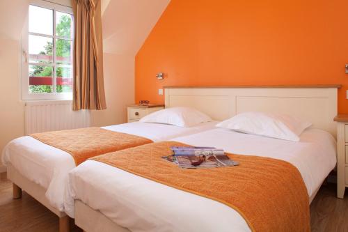 康卡勒孔克勒村庄酒店的卧室设有两张床铺,拥有橙色墙壁