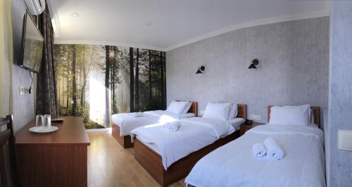 第比利斯卡兰加酒店的客房设有三张床、白色床单和窗户。