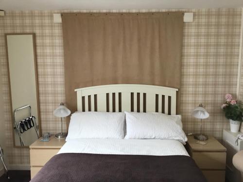 爱丁堡Ingleneuk Bed and Breakfast的一间卧室配有一张大床和两盏灯。
