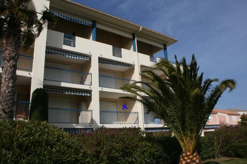 勒拉旺杜Résidence AZUR1 Appartement 251的一座白色的建筑,前面有棕榈树