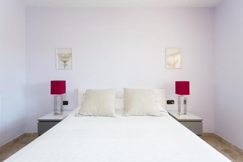 洛斯克里斯蒂亚诺斯El Ancla的卧室配有带两盏灯的白色床
