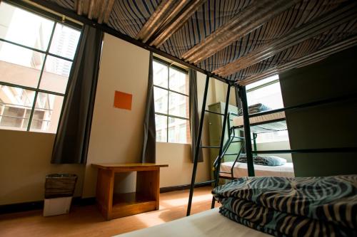 墨尔本墨尔本市背包客旅舍的客房设有一张床和一张双层床,配有窗户。