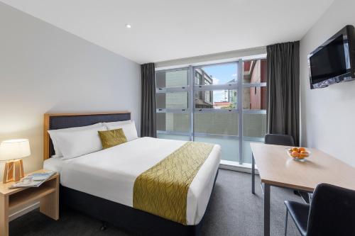奥克兰Tetra Serviced Apartments by Castle的酒店客房设有一张床和一个大窗户