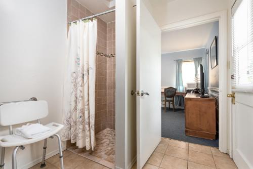 洛杉矶威尔希尔汽车旅馆的一间带步入式淋浴间的浴室,毗邻一张书桌