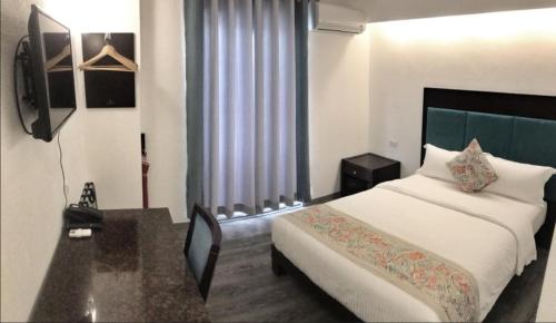 长滩岛长滩岛埃尔普尔托酒店的一间卧室配有一张床、一张书桌和一个窗户。