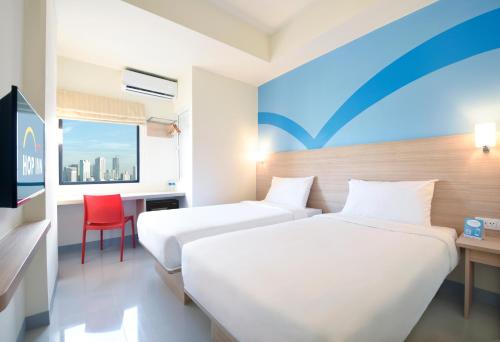 马尼拉Hop Inn Hotel Aseana City Manila的酒店客房,设有两张床和一张红色椅子