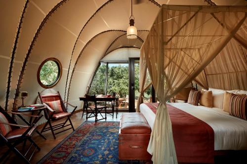 雅拉Wild Coast Tented Lodge All Inclusive的一间卧室配有天蓬床和桌椅