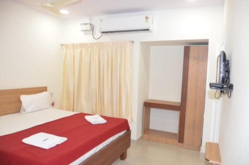 库姆巴科纳姆Raya's Inn的一间卧室配有一张带红色床单的床和一扇窗户。