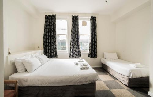 奥克兰阿尔比恩酒店的一间卧室设有两张床和窗户。