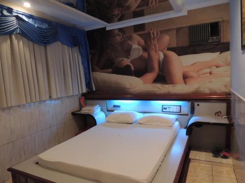 Vila AnastácioAmerica Motel (ADULT ONLY)的小房间设有两张床,墙上挂有绘画作品