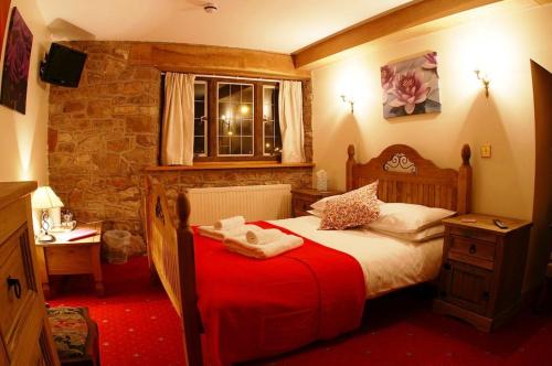 利德尼The George Inn & Millingbrook Lodge Ltd的一间卧室配有一张带红色毯子的床