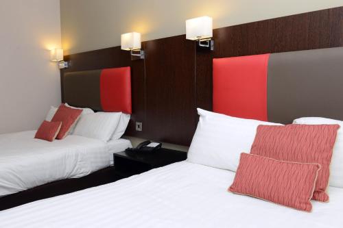 特尔福德特尔福特国际酒店的酒店客房带两张带红白色枕头的床