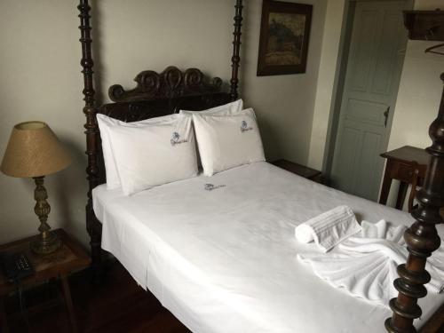欧鲁普雷图Pousada Solar da Inconfidencia - By UP Hotel - fácil acesso a Praça Tiradentes的卧室配有一张带白色床单和枕头的大床。